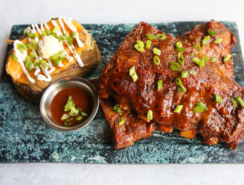 Half rack of pork ribs that are slow-roasted in a sweet mango habanero sauce and topped with scallions. Served with a loaded baked potato with cheddar, garlic butter, sour cream and scallions.