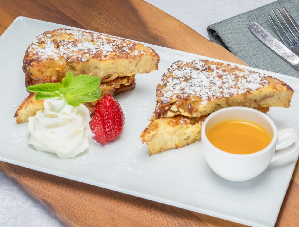 French toast battered bread pudding, strawberry, mint, powdered sugar, passion fruit rum sauce made with Captain Morgan Original Spiced Rum, whipped cream
