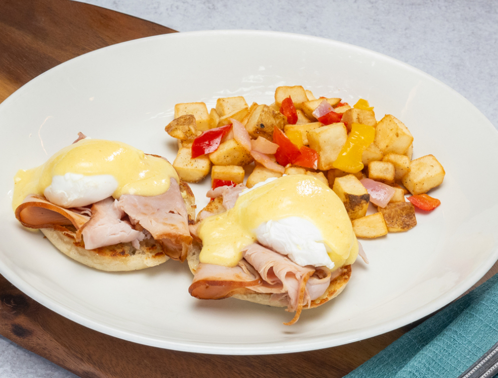 Two poached eggs, toasted English muffin, hickory-smoked ham, cayenne citrus hollandaise, choice of grits or house potatoes