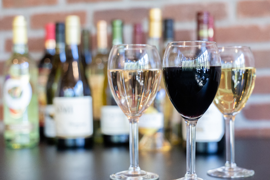 Image of glasses of wine with wine bottles in the background